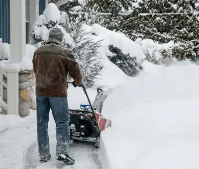 Residential snow removal technician using a snow blower to clear a home driveway and walkway in Columbus, OH